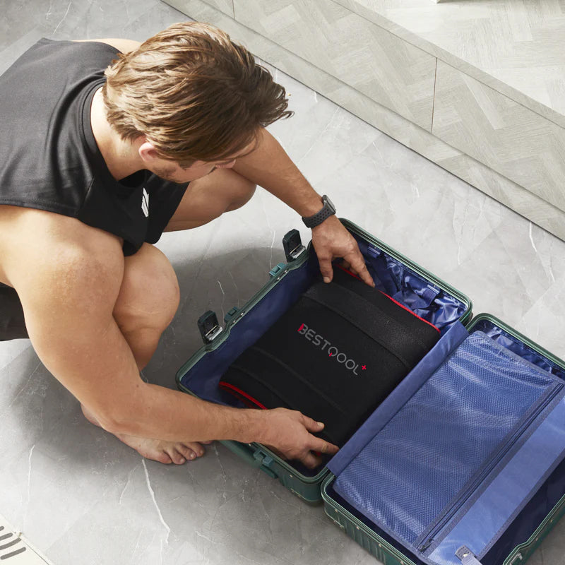 BestQool Redot M red light therapy wrap, black with red trim, being packed into a suitcase for travel.