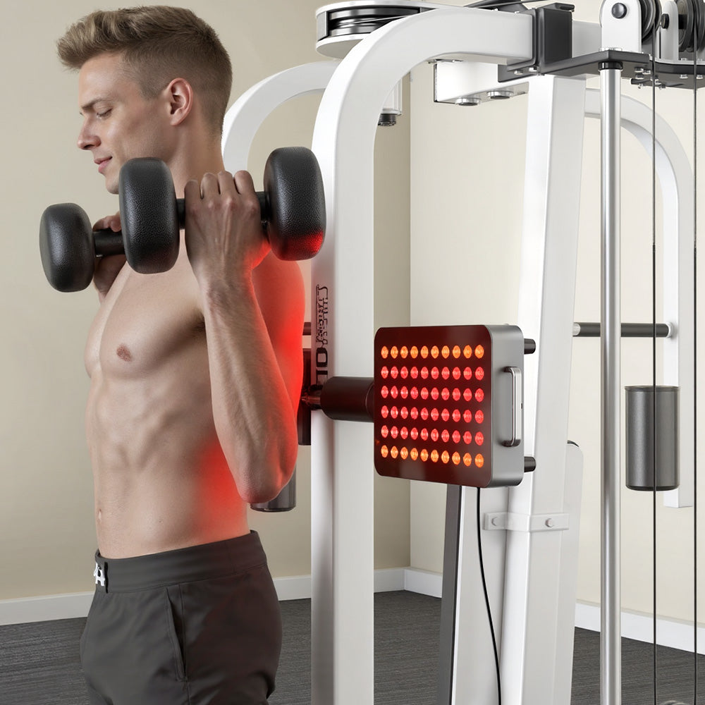 A muscular man lifting dumbbells in a gym, with the BestQool BQ60Pro red light therapy device clamped onto the fitness equipment to treat his shoulder and back area.