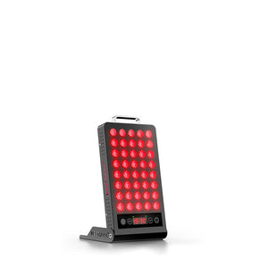 User engaging in red light therapy with portable BQ40 device on a desk.