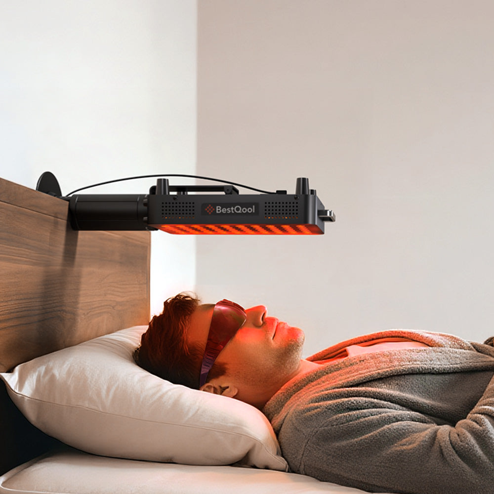 A man lying in bed wearing protective glasses and using the BestQool BQ60Pro clamp-type red light therapy device, clipped to the headboard.